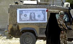 An Iraqi woman walks past a British soldier and military vehicle with a poster of a dollar bill with the Arabic writing: You can get some money, in exchange for some information". Photograph: Essam al-Sudani/AFP/Getty Images