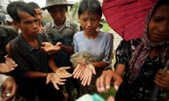 Burmese people beg for food in the rain as aid begins to arrive following cyclone Nargis