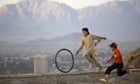 Young boys play with a bicycle tire on Cannon Mountain in Kabul