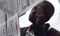 A man reads a newspaper hung up by vendors in Congo, Africa