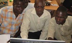 Katine residents and Amref staff gather around the computer in the media resource centre for an online chat