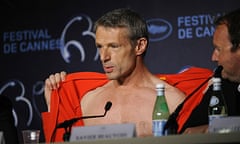 French actor Lambert Wilson removes his tracksuit top at the press conference of Des Hommes et des