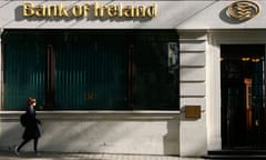 A woman passes a branch of the Bank of Ireland in London