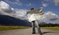 A man stands on a rural path reading a map