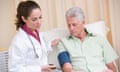 Doctor checking man's blood pressure in exam room