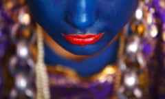 A Newari woman, with her lips and face painted to depict a deity, sits inside a house before she takes part in a parade to celebrate the Yamari Puni festival in Kathmandu, Nepal.