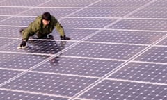 A worker cleans solar panels on the roof of a building in Taiyuan