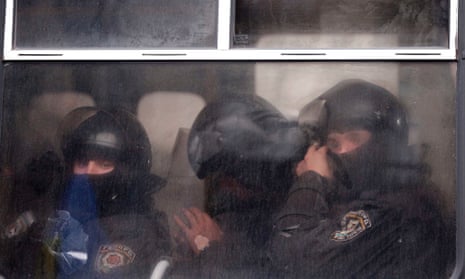 Ukranian police officer look on from their bus in front of demonstrators outside the government building in Kiev.