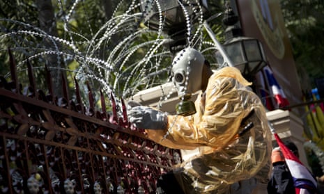An anti-government protesters wearing a gas mask cuts through barbed wire to remove a barricade in front of the central police headquarters in Bangkok, Thailand.