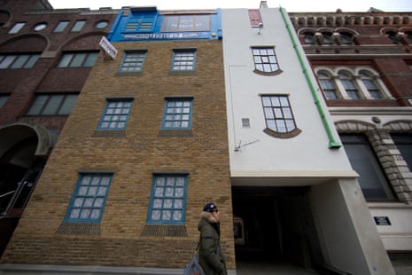 A man walks past Miner on the Moon (Upside Down House), the latest art installation by Alex Chinneck, on Blackfriars Road in central London.