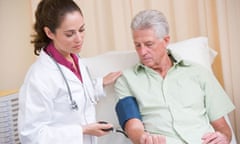 Doctor checking man's blood pressure in exam room