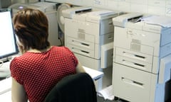 A woman working in an office near printers
