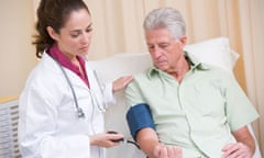 Doctor checking man's blood pressure in exam room