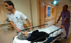 Healthcare professionals moving an old woman on a gurney in an hospital