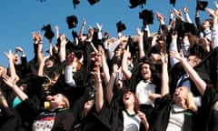 A group of university students graduating on graduation day, throwing their caps in the air, UK