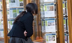 Young woman looking at houses in estate agent window London England UK