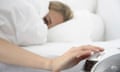 Woman in bed with hands on alarm clock.