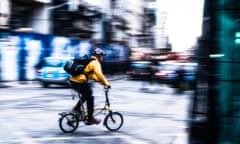 Cyclist wearing a bright yellow jacket is taking a right turn into London's Tottenham Court Road, London