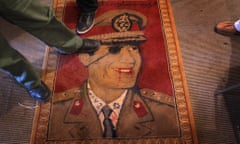 Libyans step on a carpet featuring Libyan leader Muammar Gaddafi on February 25, 2011 in Benghazi, Libya. Gaddafi was killed in October 2011.