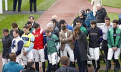 Jockeys observing a minute's silence at Cheltenham following the death of Dessie Hughes