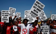 Protestors wave placards with the writing "Don't let the police get away with murder" as the judicial commission inquiry visit the site where 34 striking platinum miners were shot dead.