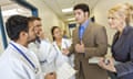 Hospital administrators talking with doctors in busy hallway