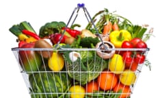 Photo of a wire shopping basket full of fresh fruit and vegetables, isolated on a white background