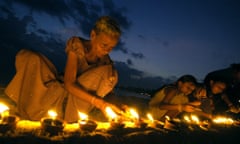 A Sri Lankan woman lights an earthenware lamp as she sits with others at Unawatuna Beach in Galle, some 123 km south of Colombo, 26 January 2005. Sri Lankans lit some 40,000 lamps in memories of those killed by tsunami waves which struck 26 December 2004