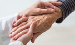 a woman holds an old man's hand.