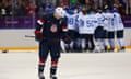 Team USA's Zach Parise skates away as Finland celebrates their win in their men's ice hockey bronze medal game.