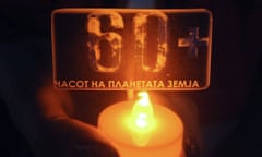 An activists of the Red Cross NGO holds a candle with the number "60+", during Earth Hour in Skopje main square, Macedonia.