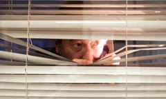A man peering through a set of blinds