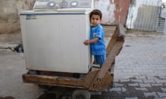 An Iraqi child stands on a cart loaded with a washing machine in Sadr City in Baghdad.