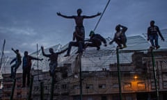 Migrants climb a fence between Morocco and the Spanish enclave of Melilla.