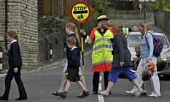 Lollipop lady helps schoolchildren cross road 