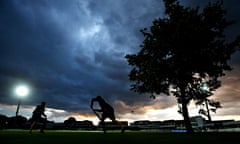 Cricket players under dark clouds