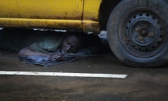 A man, said to be showing symptoms of Ebola, lies under a car after being put there in detention by the Liberian army on the second day of the government's Ebola quarantine on the West Point neighbourhood in Monrovia.