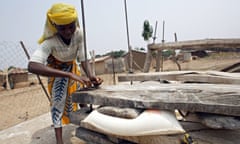 a woman using firewood dryer to dry cassava flour