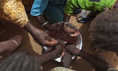 aryam Sy and five of her nine children share a meager bowl of tamarind-flavored porridg