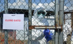 On 13 November 2014, a health worker wearing personal protective equipment (PPE) closes a gate leading out of the green (safe) zone, at a newly built Ebola treatment unit (ETU) in Monrovia.