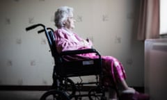 An elderly lady sits in a wheelchair looking out of the window