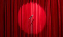 Microphone in spots light on empty stage with red curtain behind