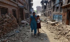 Nepalese schoolgirl walks with her mother past damaged buildings to school in Bhaktapur on the outskirts of Kathmandu on May 31, 2015.