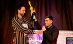 Leo Kearse, left, winner of the UK Pun Championships, with a bottle of bubbly, a rubber chicken and Lee Nelson