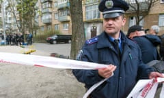 A police officer cordons off the area as police experts examine the body of prominent pro-Russian journalist Oles Buzyna.