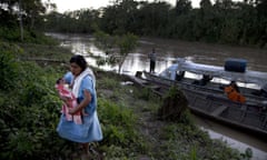 March 16, 2015 photo, Ashaninka Indian Karen Shawiri carries her baby boy away from Putaya River in Saweto, Peru. Shawiri was elected secretary of her hamlet less than one year ago