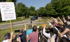 Protesters shout and wave a placard that