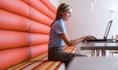 A woman works on her laptop in a modern cafe