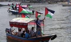 Palestinians hold their national flag as they ride boats during a rally to show support for activists on the Freedom Flotilla III at the seaport of Gaza City on 24 June 2015.