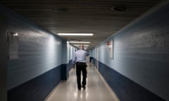 Rear view of a prison guard walking along corridor.